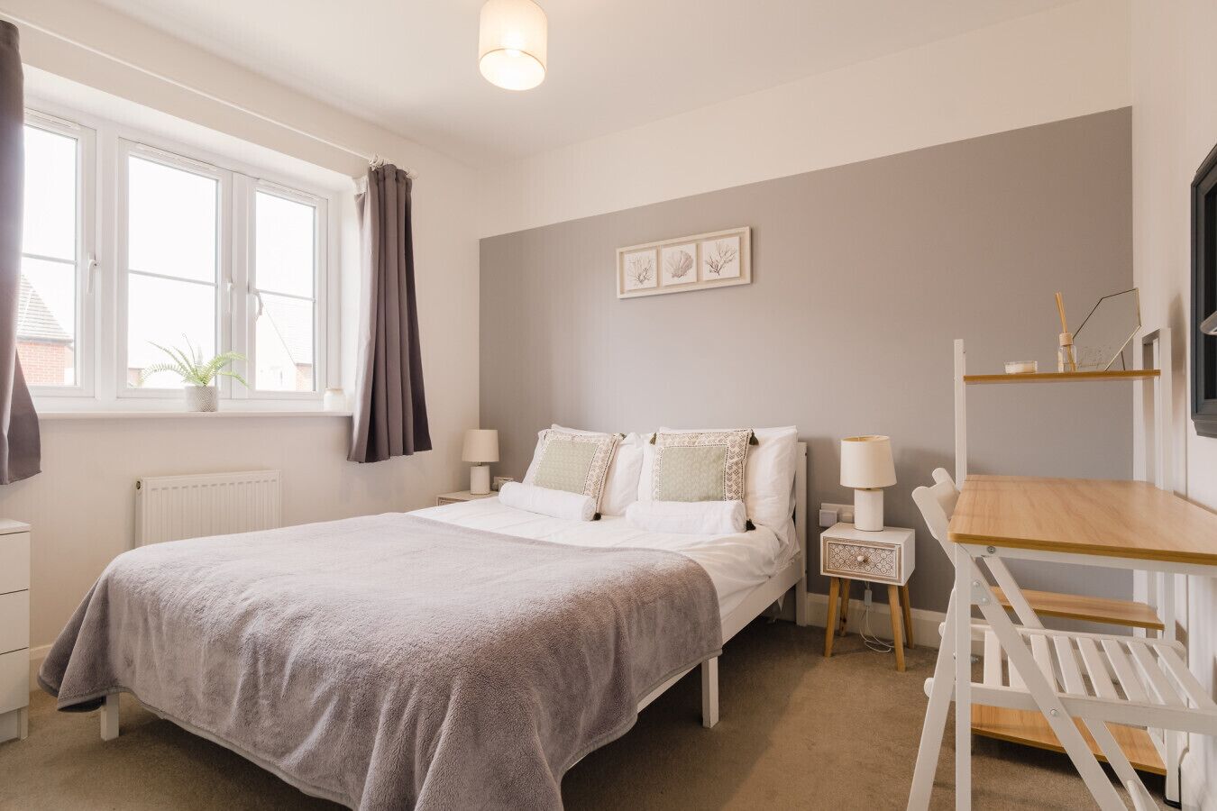 Une chambre à coucher avec un lit, des tables de chevet, un bureau et une fenêtre avec des rideaux.