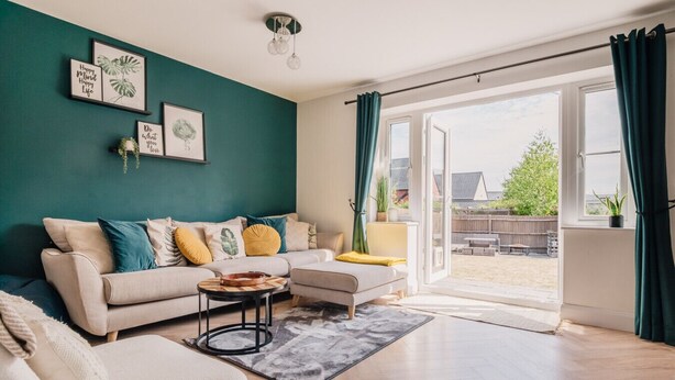 A living room with a sofa, a coffee table, and a view of the outdoors through a sliding glass door. - Beautiful 3 Bedroom Home Near Worcester (Kempsey)