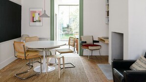 A modern living room with a round dining table, two chairs, a sofa, and a fireplace. - Beautiful 3 Bedroom Home in Bristol (Bristol)