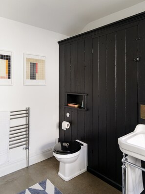 Un baño moderno con tocador negro, inodoro blanco y barra para toallas.