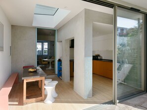 Un interior moderno con comedor, cocina y un ventanal corredero de vidrio que da a un espacio exterior.