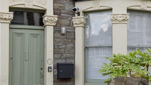 A stone facade with a green door, a stone wall with a security box, and a window with blinds. - Beautiful 3 Bedroom Home in Bristol (Bristol)