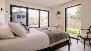 Un dormitorio con una cama grande, una silla y vistas al exterior.