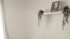 Une chambre à coucher avec un lit, des oreillers, une table de chevet et une plante suspendue.