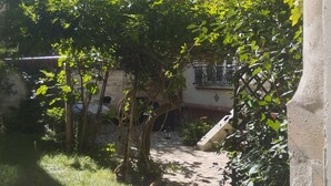 Un bâtiment en pierre avec un jardin et un chemin qui mène à une porte.