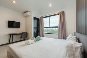 A hotel room with a bed, a desk, a chair, a television, and a window with curtains. - 1BR Condo Pool Gym Near Beach C237 (Choeng Thale)
