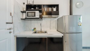 Een kleine keuken met een magnetron, oven en koelkast.