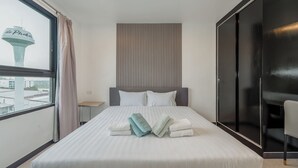 Een moderne hotelkamer met een groot bed, uitzicht op een toren en een schuifdeurkast.