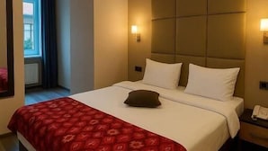 A hotel room with a large bed, a headboard, two bedside lamps, and a telephone on the nightstand. - Bella Garden Hotel (Baku)