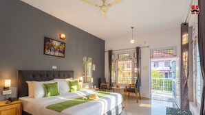 A modern hotel room with a large bed, a painting on the wall, a balcony with a view, and a desk with chairs. - Moustache Hostel Bir (Baijnath)