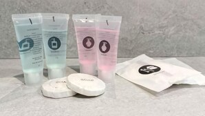 Τέσσερις σωλήνες με προϊόντα περιποίησης δέρματος, δύο στρογγυλά λευκά επιθέματα και ένα πακέτο με λευκά μαντηλάκια πάνω σε μια ανάγλυφη επιφάνεια.