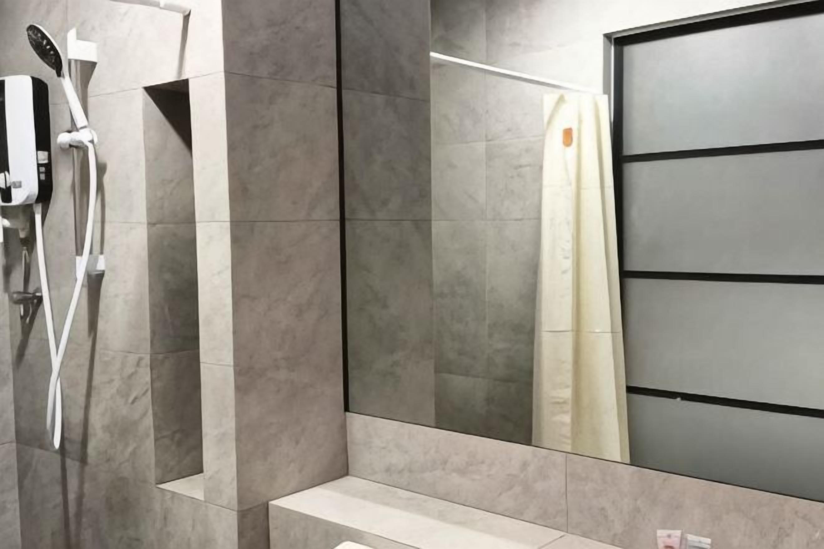 A modern bathroom with a shower, a mirror, and a toilet.