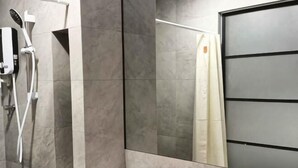 Un baño moderno con ducha, espejo y retrete.