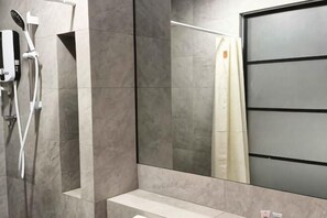 A modern bathroom with a shower, a mirror, and a toilet.
