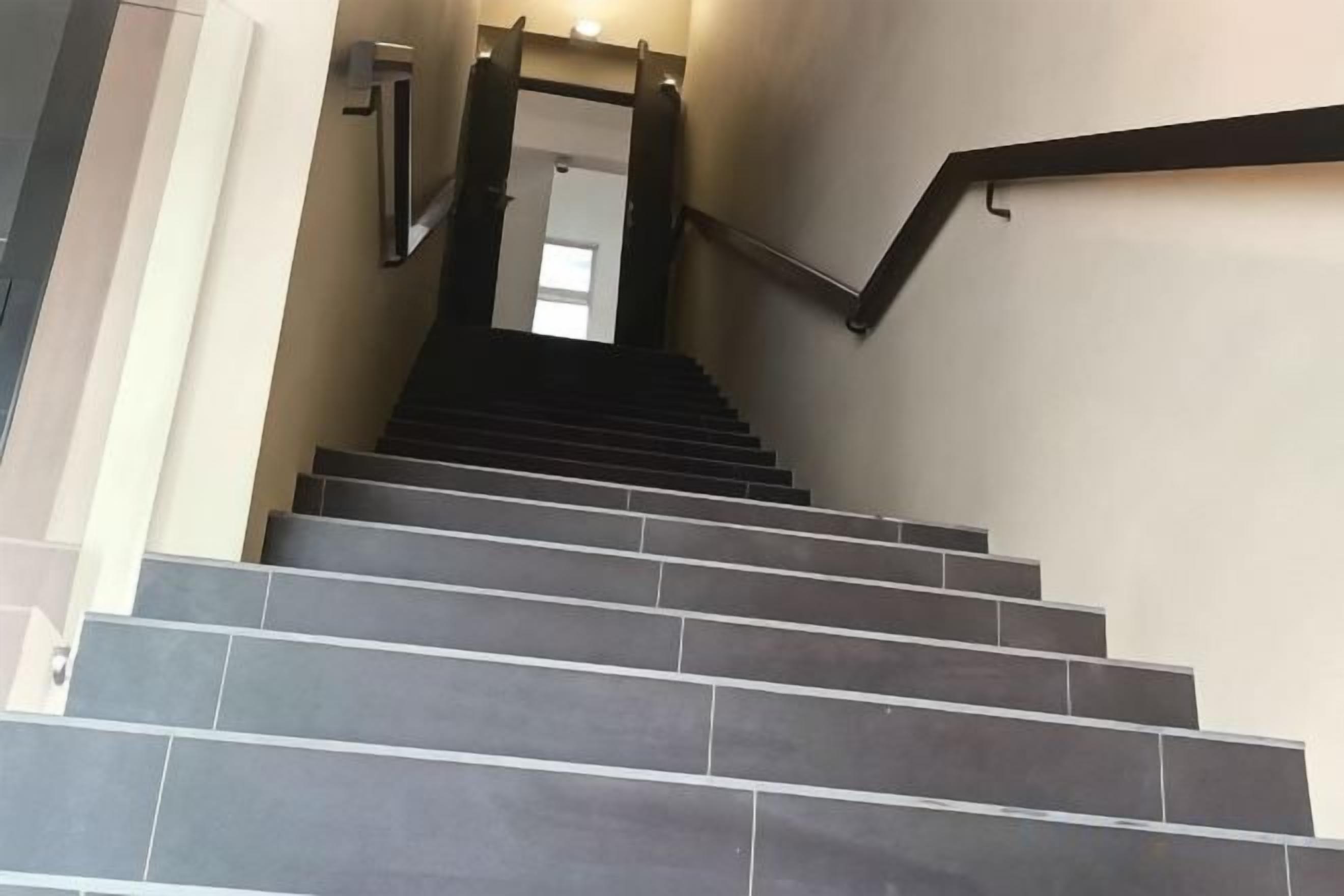A staircase with a handrail and a door at the top.