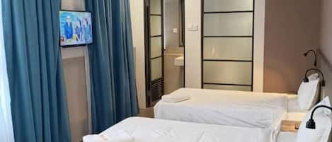 A hotel room with two beds, a television, and a mirror.