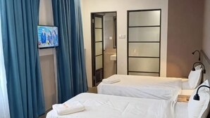 Ένα δωμάτιο ξενοδοχείου με δύο κρεβάτια, μια τηλεόραση, έναν καθρέφτη και μια ντουλάπα.