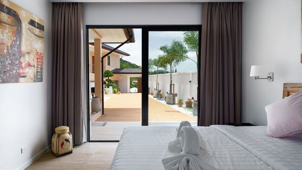 A hotel room with a bed, a towel, a suitcase, and a view of the outdoor area. - Tilawan Villa - Cozy 3 Bedrooms Pool Villa in Chalong (Chang Wat Phuket)