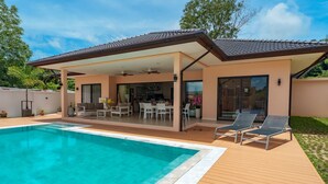 A modern house with a swimming pool, a covered patio with outdoor furniture, and a view of the surrounding greenery. - Tilawan Villa - Cozy 3 Bedrooms Pool Villa in Chalong (Chang Wat Phuket)