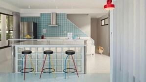 Een moderne keuken met een centraal eiland, barstoelen en een hanglamp.