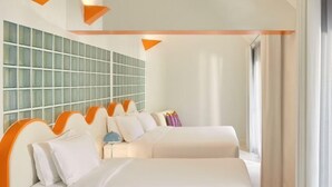 Een hotelkamer met een groot bed, een zithoek met oranje accenten en een wand betegeld met een patroon.