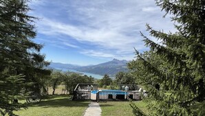 Ein Poolbereich mit einem gepflasterten Weg, umgeben von Bäumen und mit Blick auf eine Berglandschaft.