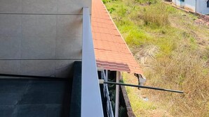 Un balcón con vista a una zona costera, que incluye casas y una playa.