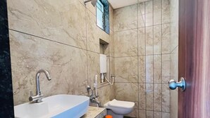 Un baño con lavamanos blanco, inodoro y zona de ducha.