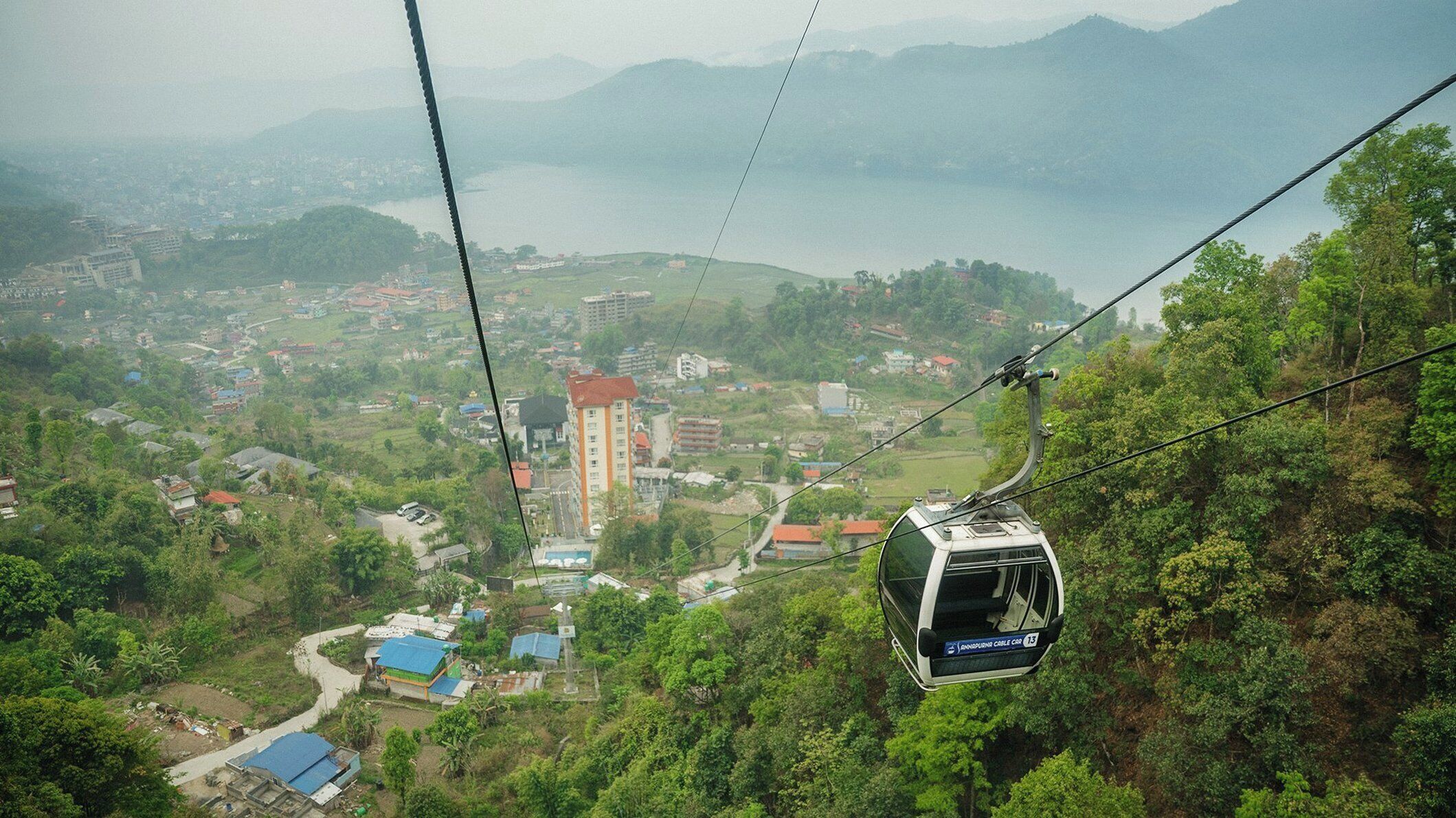 A cable car with a view of a town and mountains in the background.