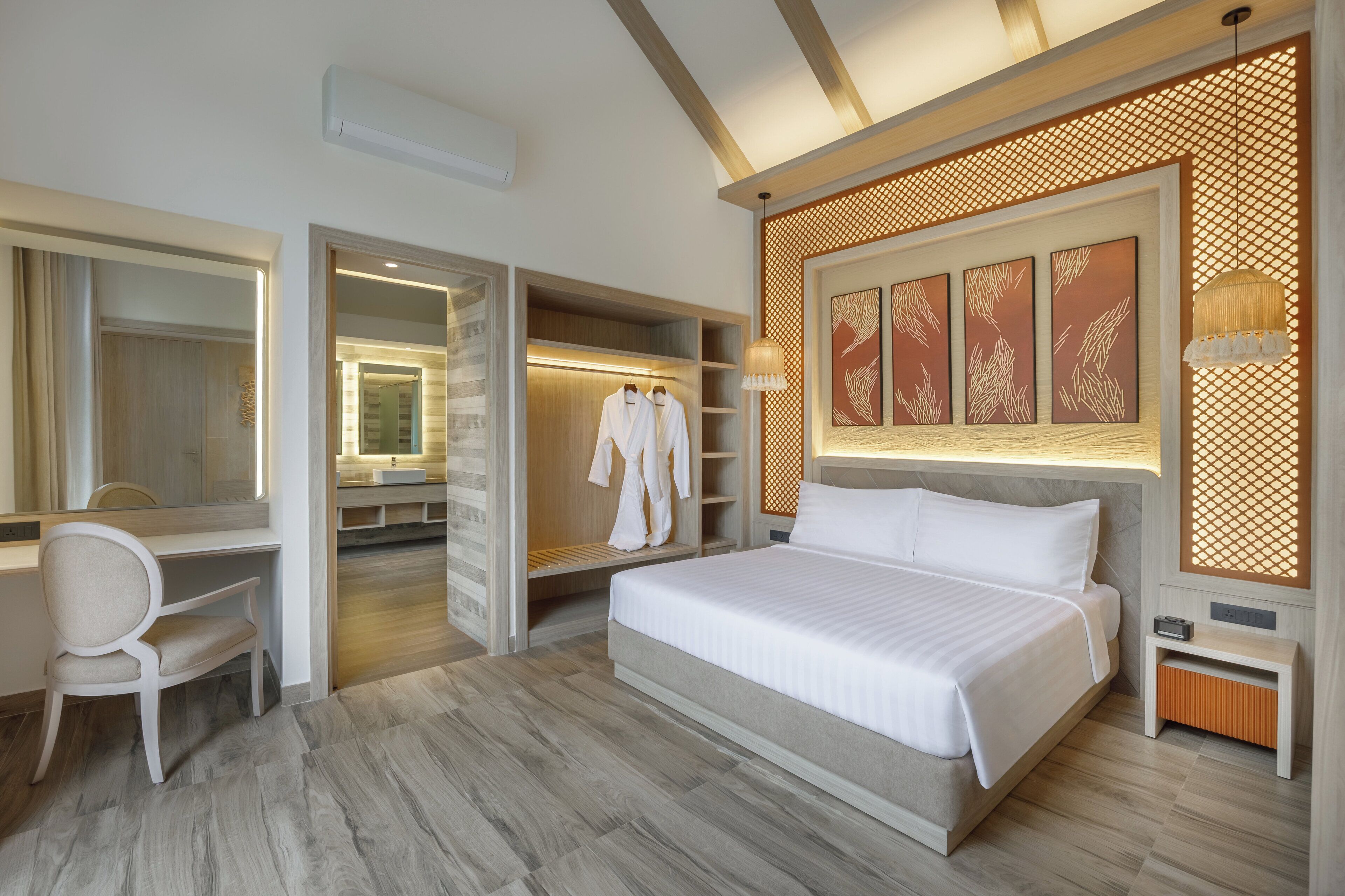 A modern hotel room with a large bed, a desk, and a walk-in closet.