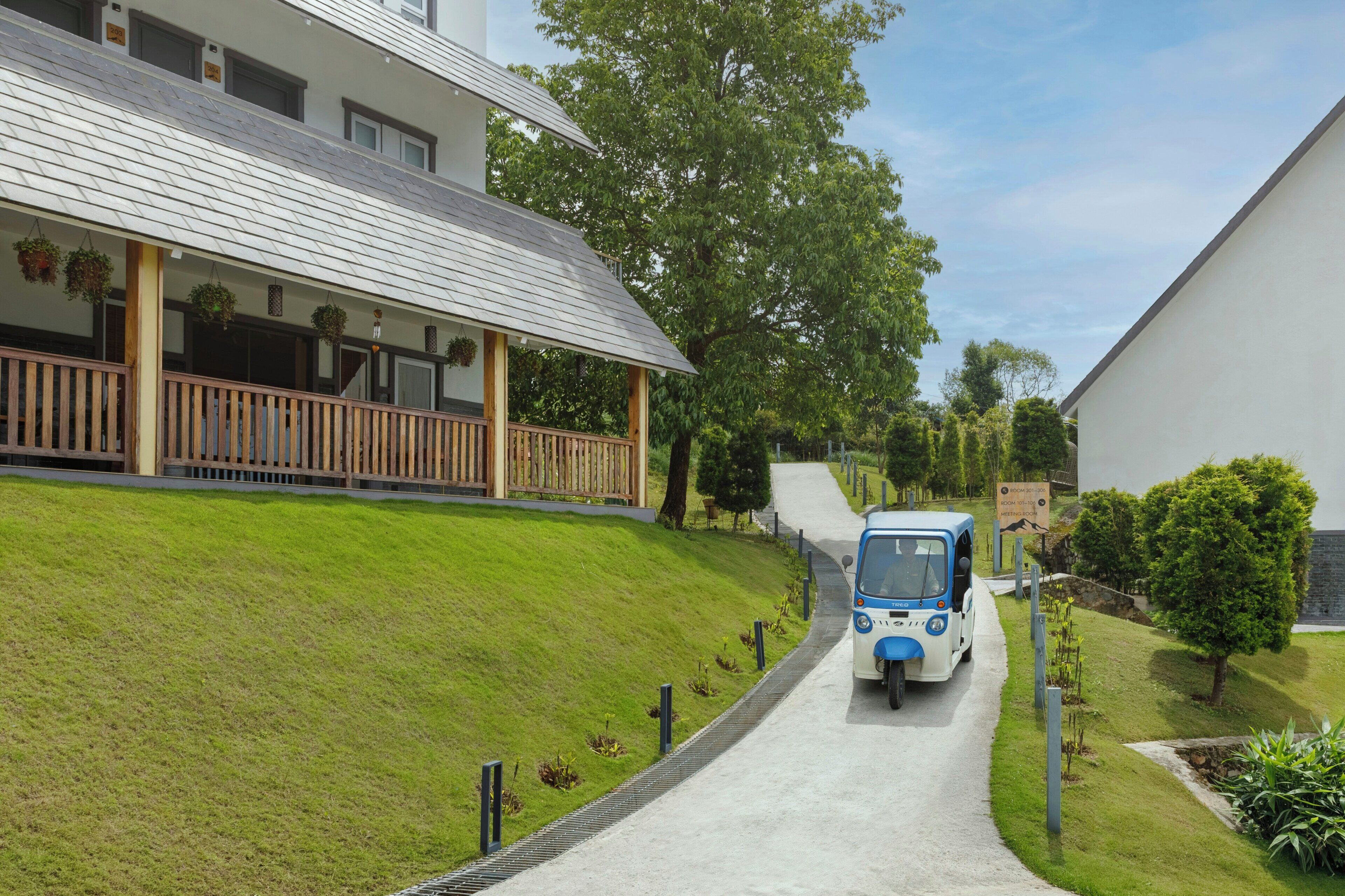A pathway leading to a building with a covered porch and hanging plants.