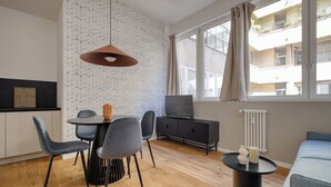 Egy modern nappali étkezővel, nagy ablakokkal és kilátással egy épületre.