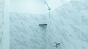 A bathroom with marble walls, a shower, and a sink. - Skybox Pension House by RedDoorz (Iloilo City)