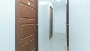 A hallway with wooden doors and white walls. - Skybox Pension House by RedDoorz (Iloilo City)