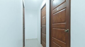 A narrow hallway with wooden doors on either side. - Skybox Pension House by RedDoorz (Iloilo City)