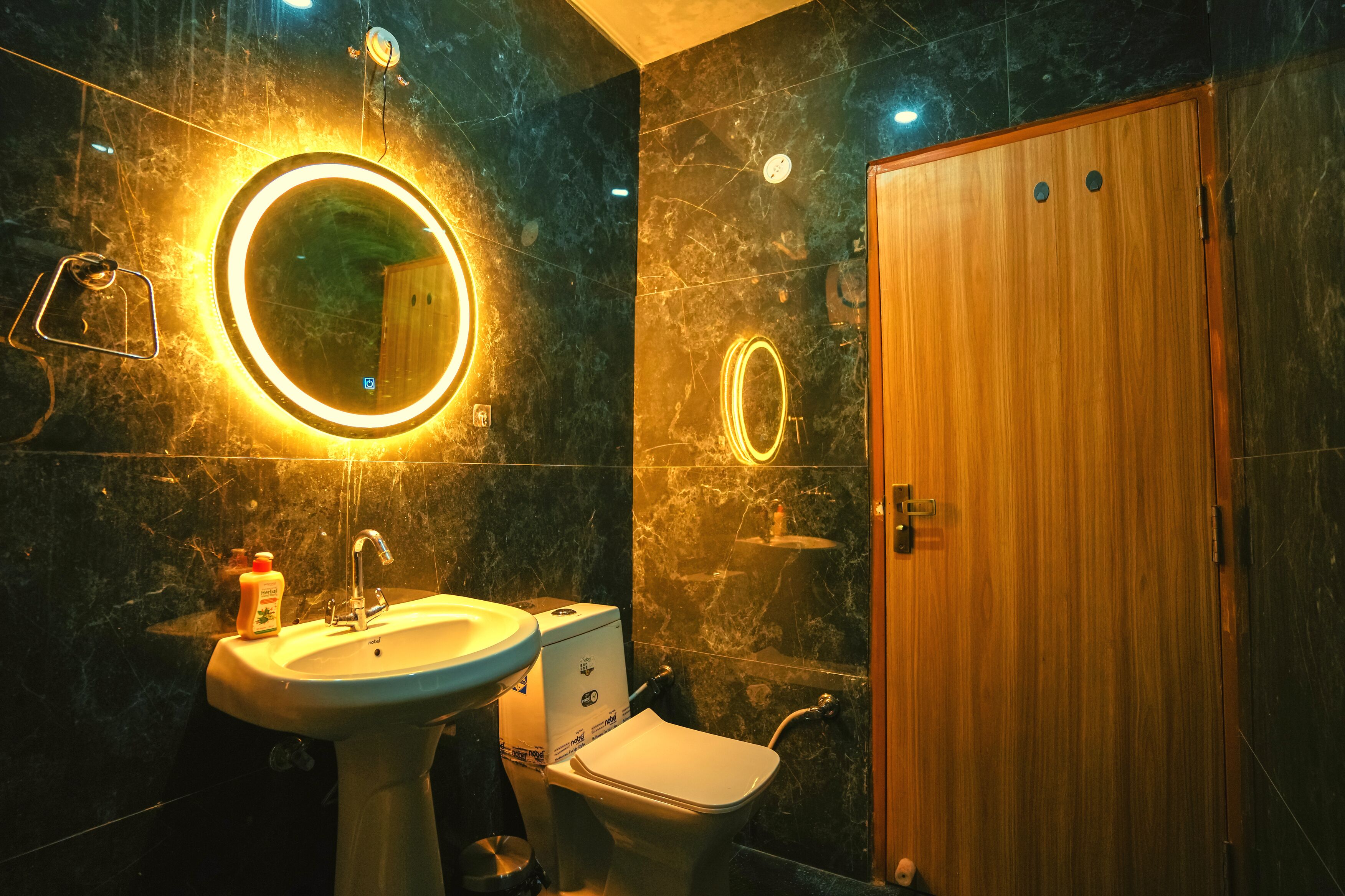 Een badkamer met een wastafel, spiegel, toilet en houten deur.
