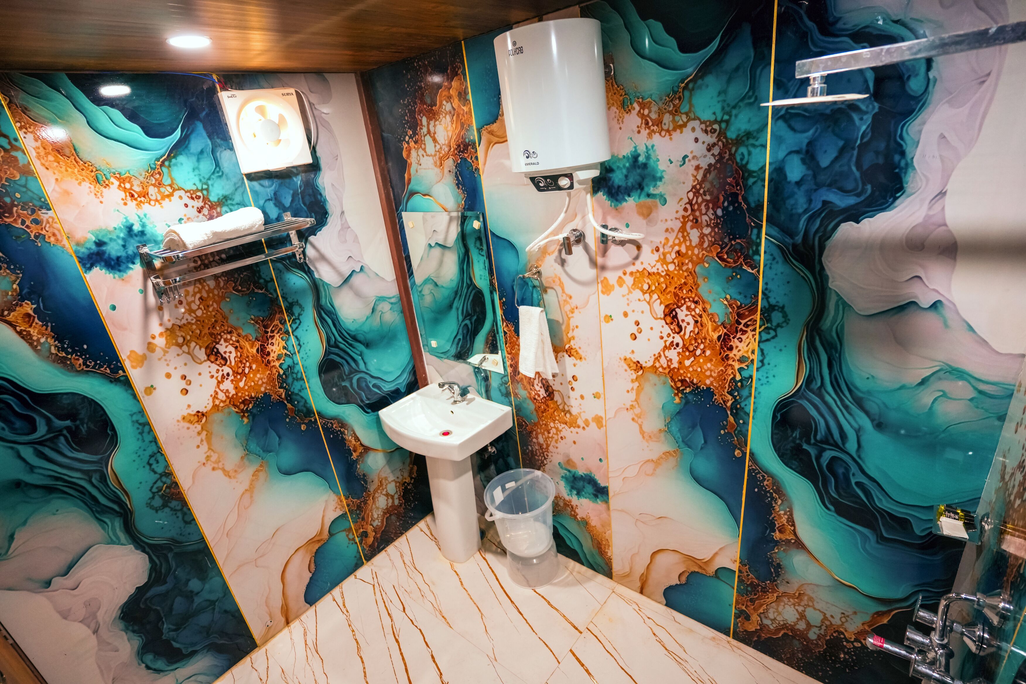 A bathroom with a marble wall, a sink, a towel rack, and a toilet.