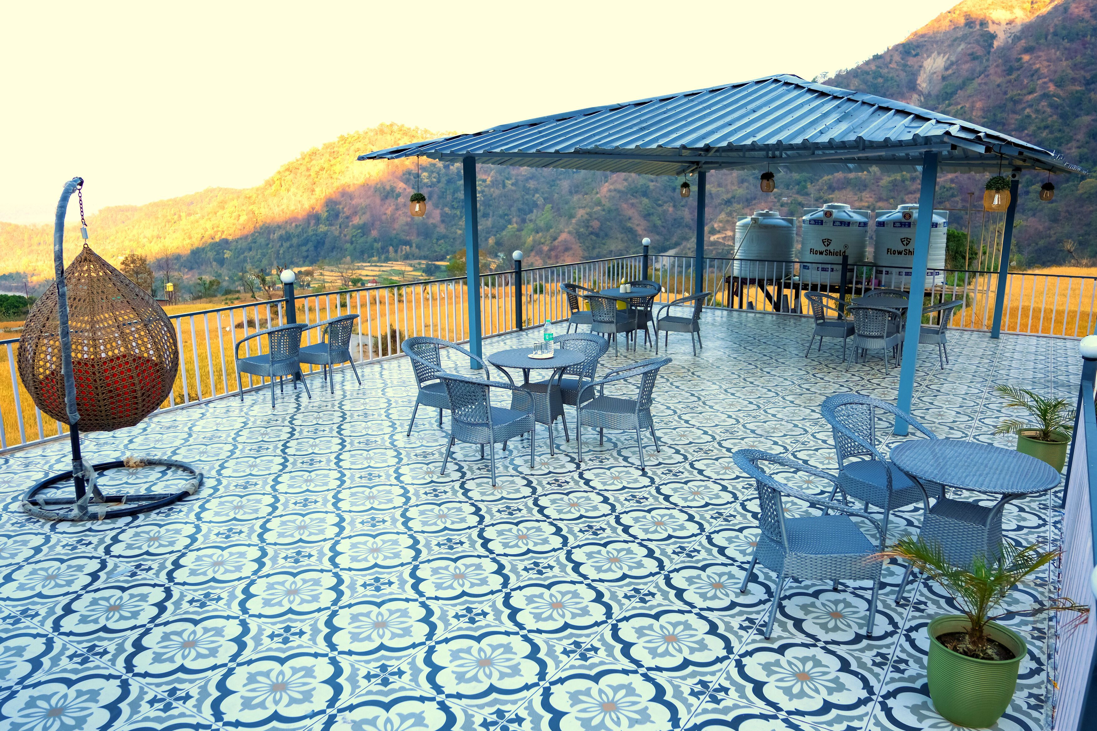 A terrace with patterned flooring, outdoor seating, and a view of a mountainous landscape.