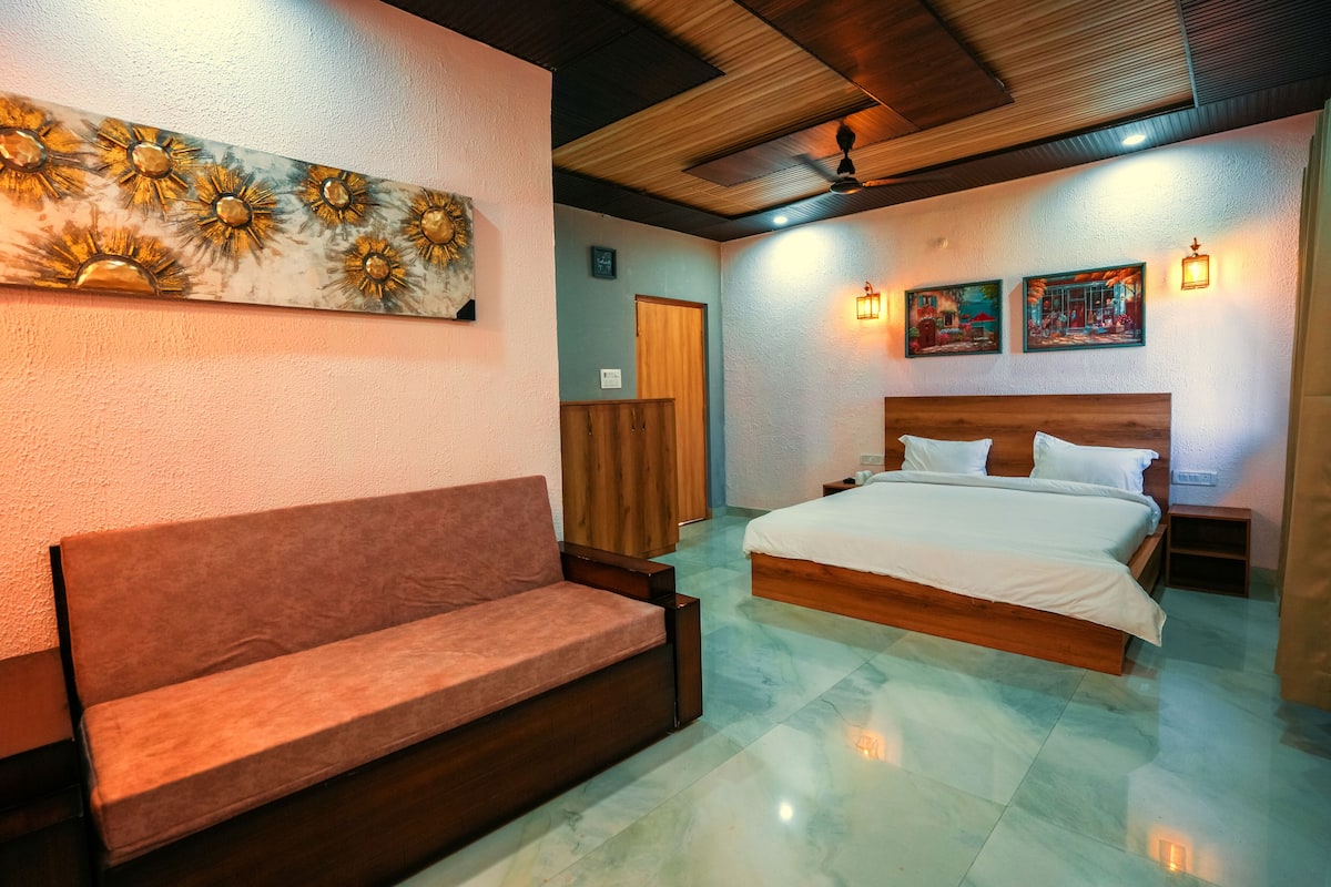 A bedroom with a bed, a sofa, and artwork on the walls.