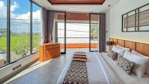 A modern bedroom with a large bed, a wooden headboard, and a view of a green landscape through large windows. - Villa Sudut Padi Ubud (Bali)