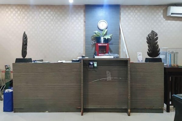 A reception desk with a clock, a red telephone, and decorative items. - San Marino JY7 Rentals by RedDoorz (Cebu City)