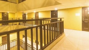 A multi-level interior with a central staircase, black railings, and yellow walls. - San Marino JY7 Rentals by RedDoorz (Cebu City)