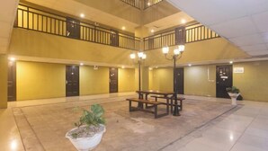 A spacious indoor area with a high ceiling, a central seating area with benches, and a staircase leading to an upper level. - San Marino JY7 Rentals by RedDoorz (Cebu City)