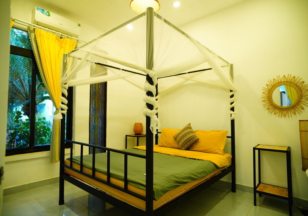 Ein Himmelbett mit Baldachin, ein kleiner Tisch, ein Spiegel und ein Fenster mit Vorhängen.