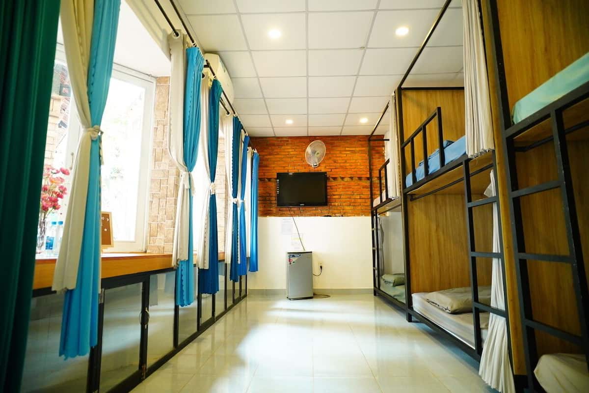 Un dormitorio con literas, televisor y un refrigerador pequeño.