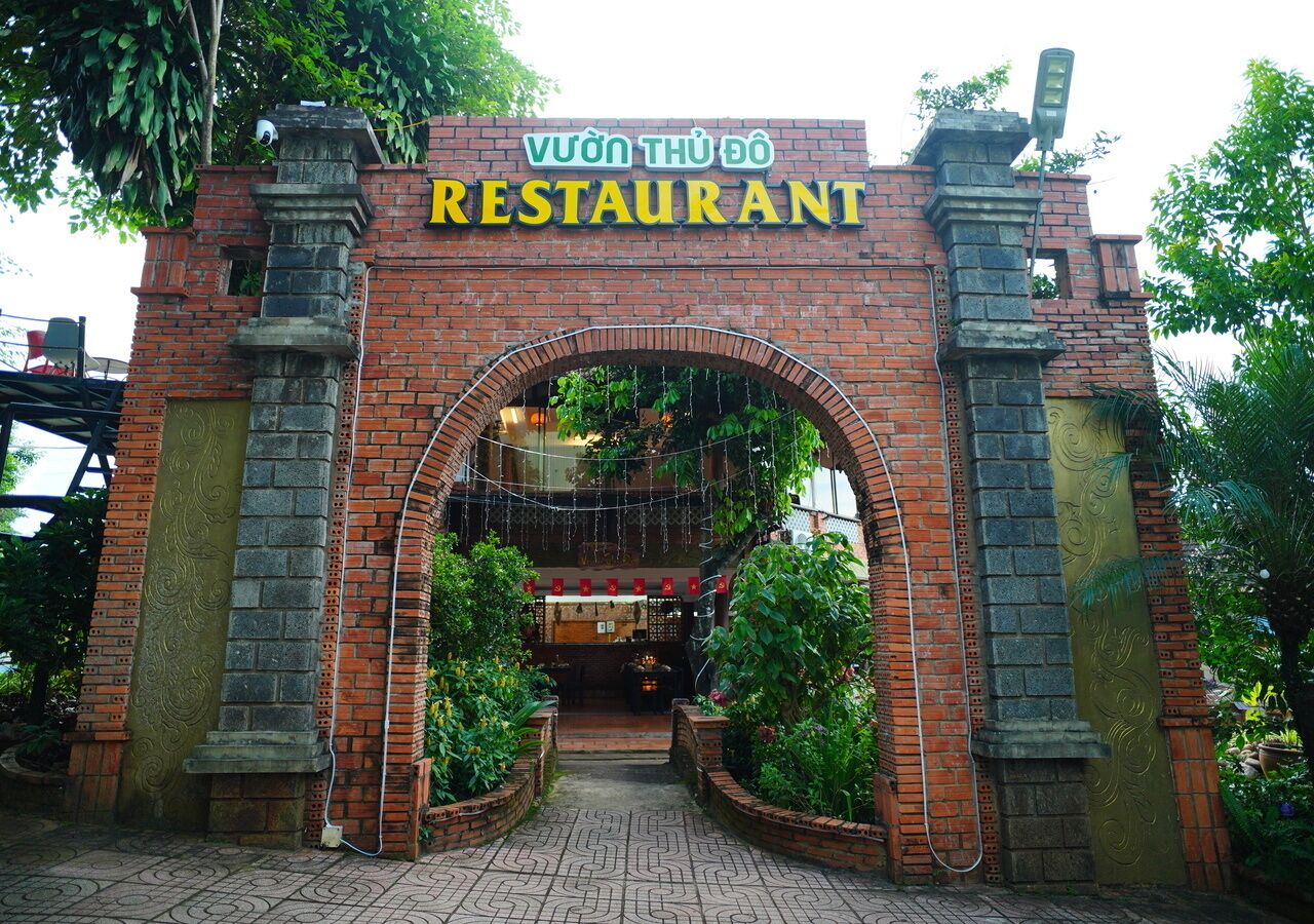 Una entrada a un restaurante con un arco de ladrillo y un letrero encima.