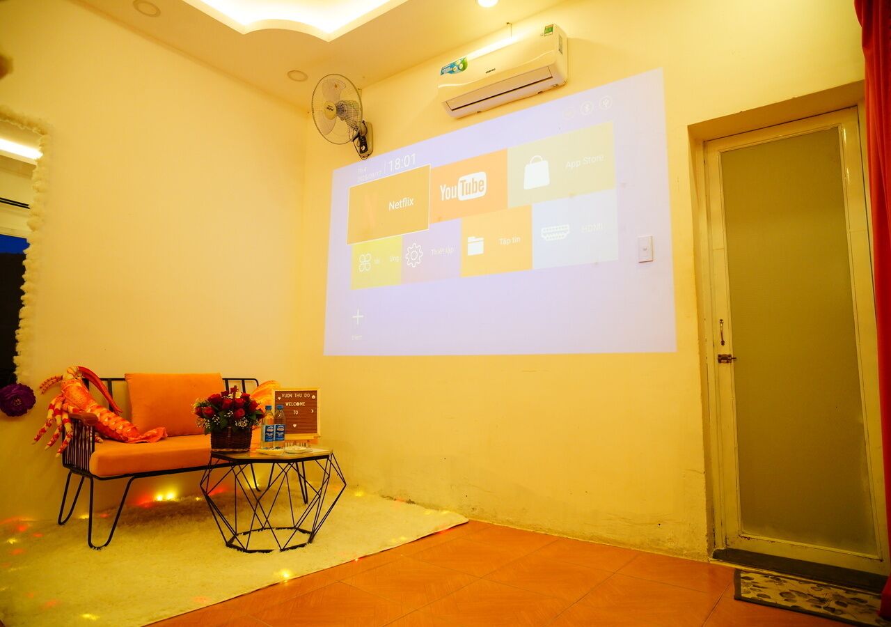 Een kamer met een bank, een salontafel en een scherm waarop app-iconen worden getoond.