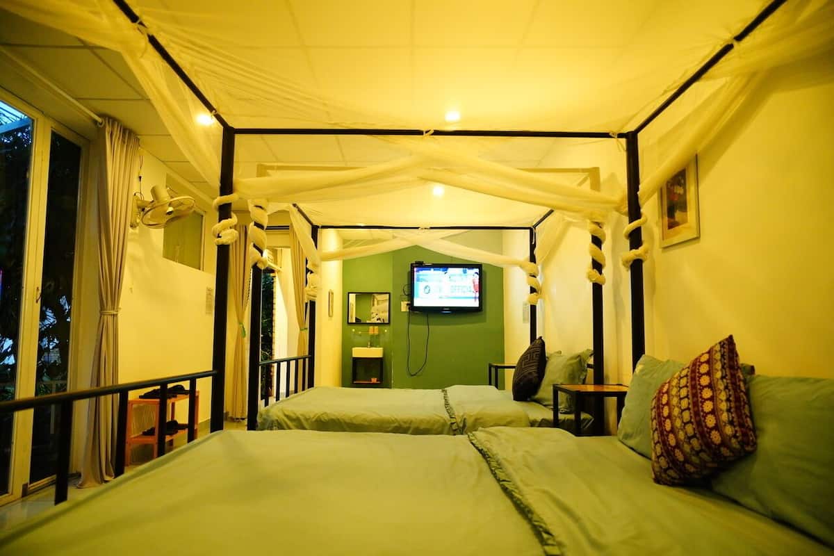 Una habitación con una cama, un televisor y una pared verde.