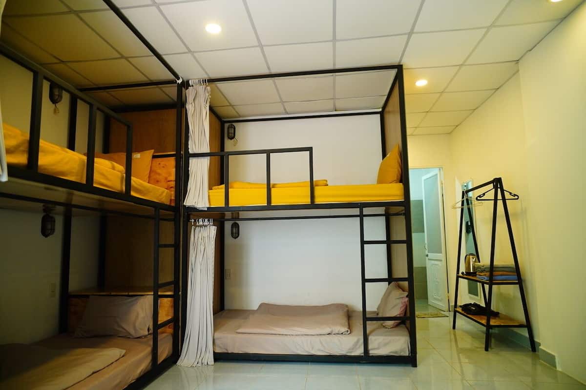 Dormitorio con literas, una estantería y una cortina.