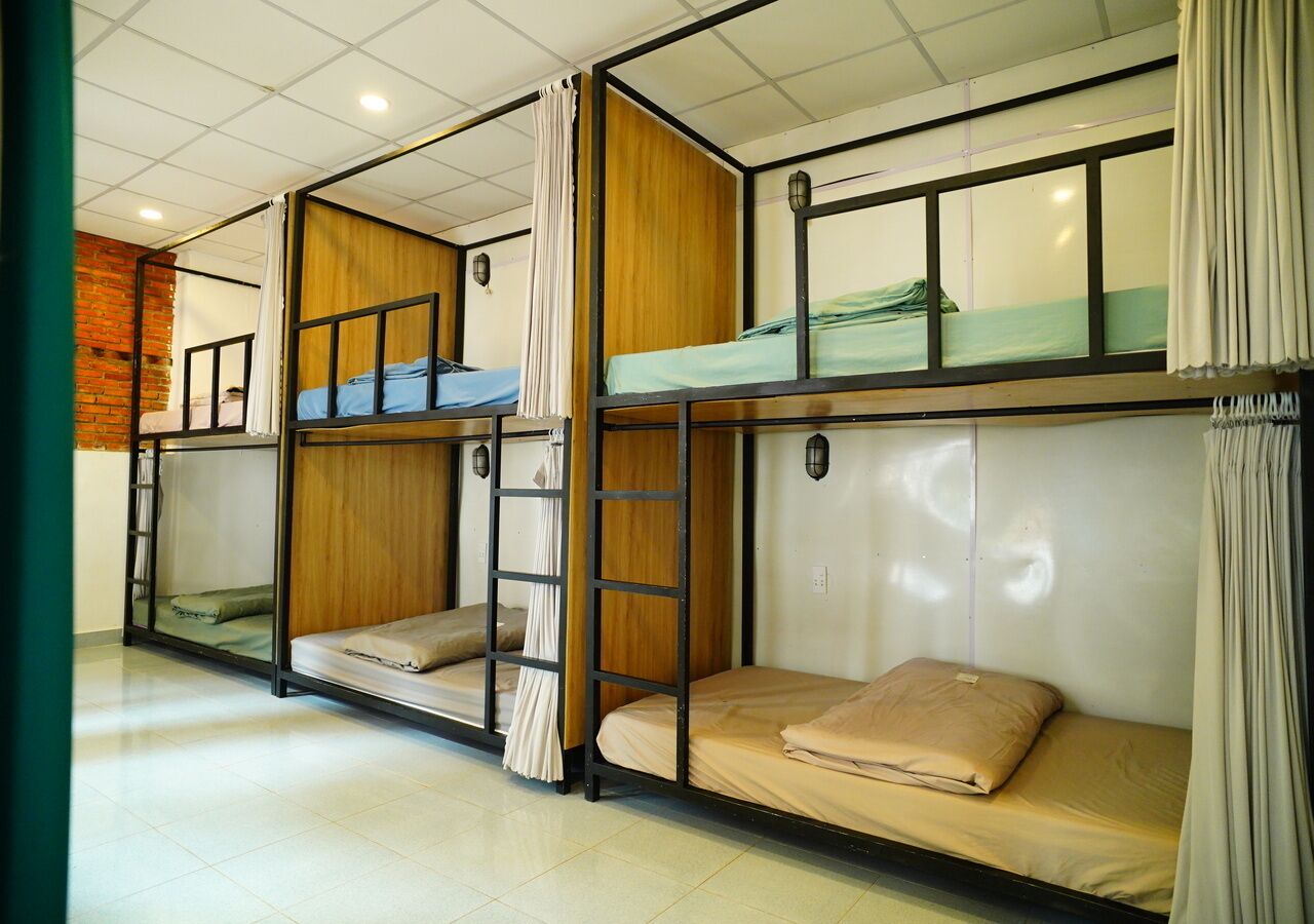 A dormitory room with bunk beds, a ladder, and a brick wall.